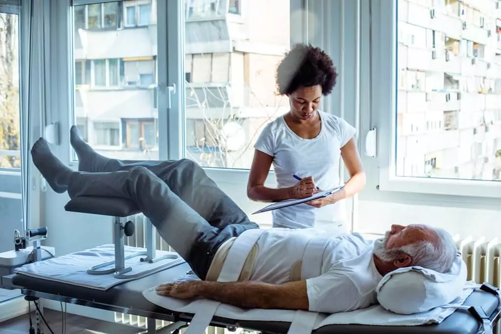 fisioterapeuta avaliando paciente idoso